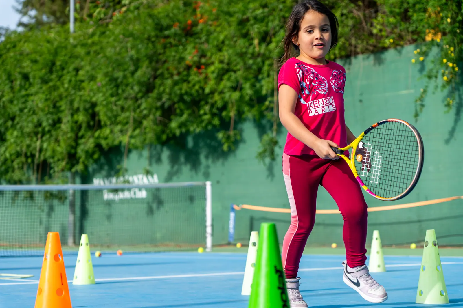Alumna de mini-tenis entre conos en la pista del club